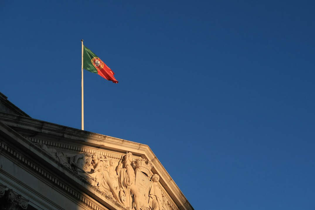 Fachada de edifício governamental clássico em Lisboa com bandeira de Portugal